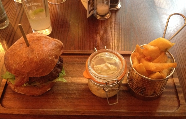 A well lit photo of the burger and fat chips from Hove Place on a wooden board